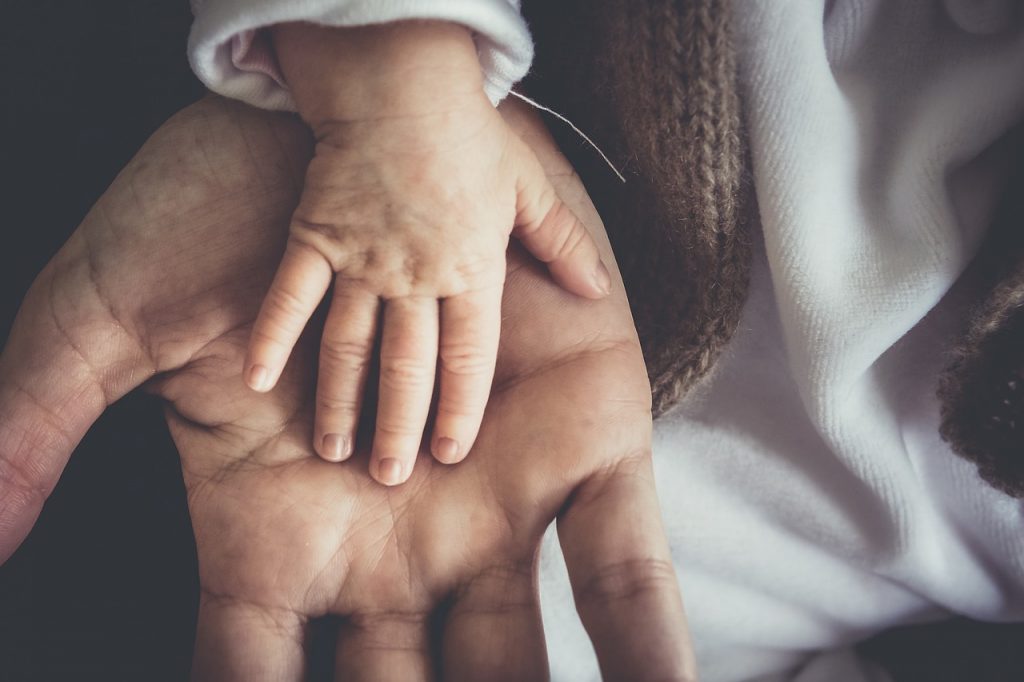 dłoń dziecka położona na dłoni ojca
