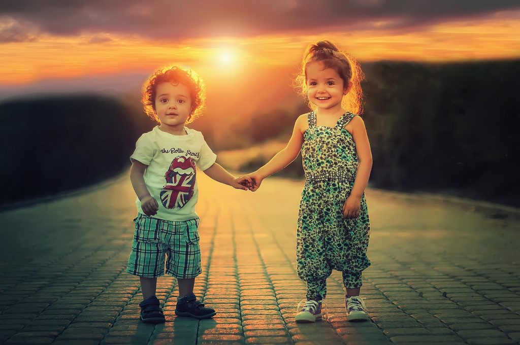 Dzieci trzymające się za ręce przy zachodzie słońca