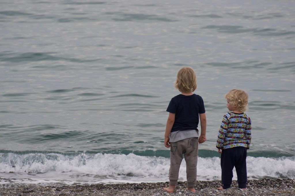 Dzieci stoją na brzegu morza.