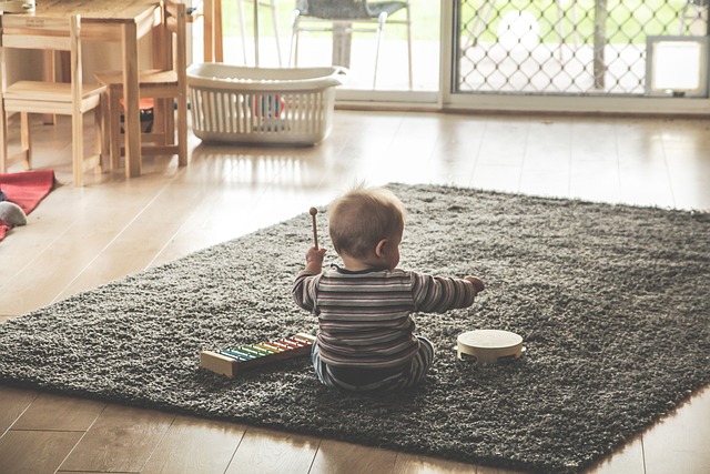 Dziecko bawi się zabawka na kiju siedząc na dywanie